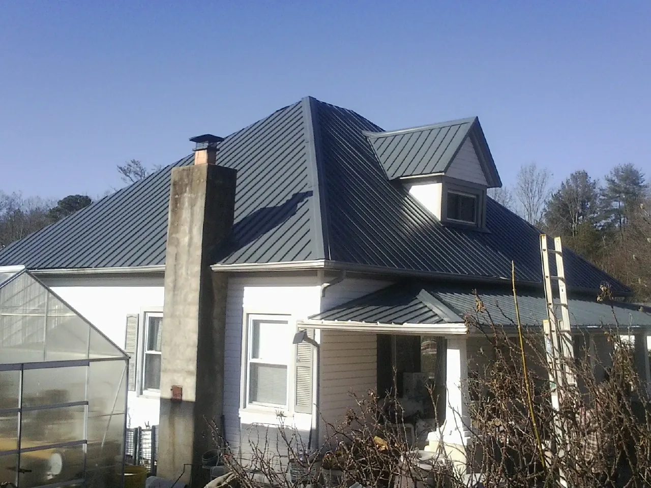 Dark blue standing seam metal roof on a white farmhouse with dormer — Slate & Tile Roof Repair by Roofing Brothers in Liberty Mills