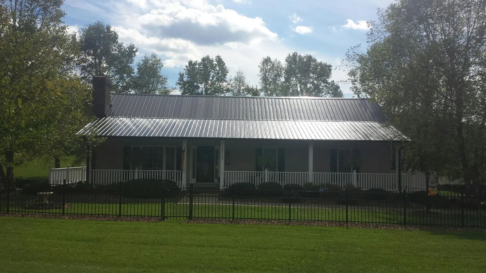 Gray metal roof on a brick ranch with a full width front porch — Gutter Guard Installation work by our crew in Liberty Mills
