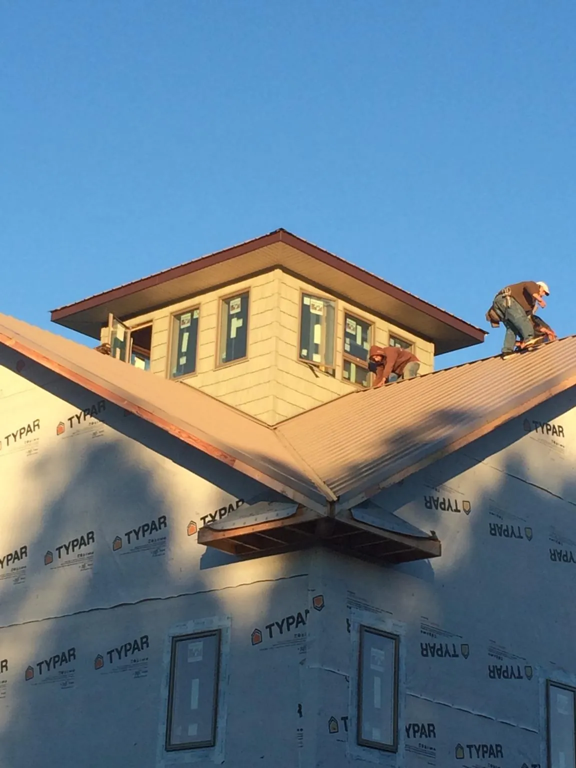 Roofers working around a rooftop cupola on a new metal roof at sunset — Roof Waterproofing in Liberty Mills by Roofing Brothers